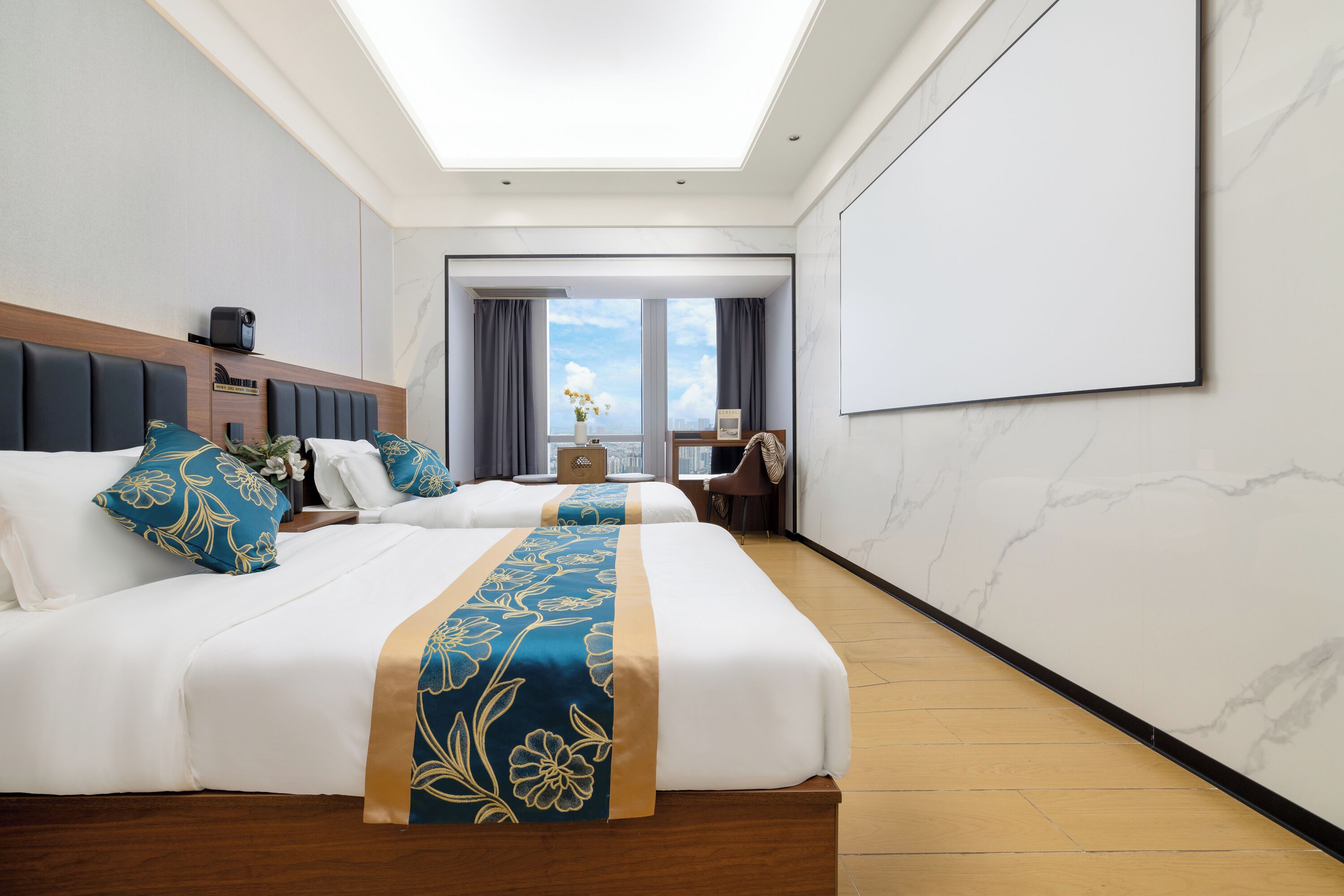 Een hotelkamer met twee bedden, een groot raam, een flatscreen televisie en een houten vloer.