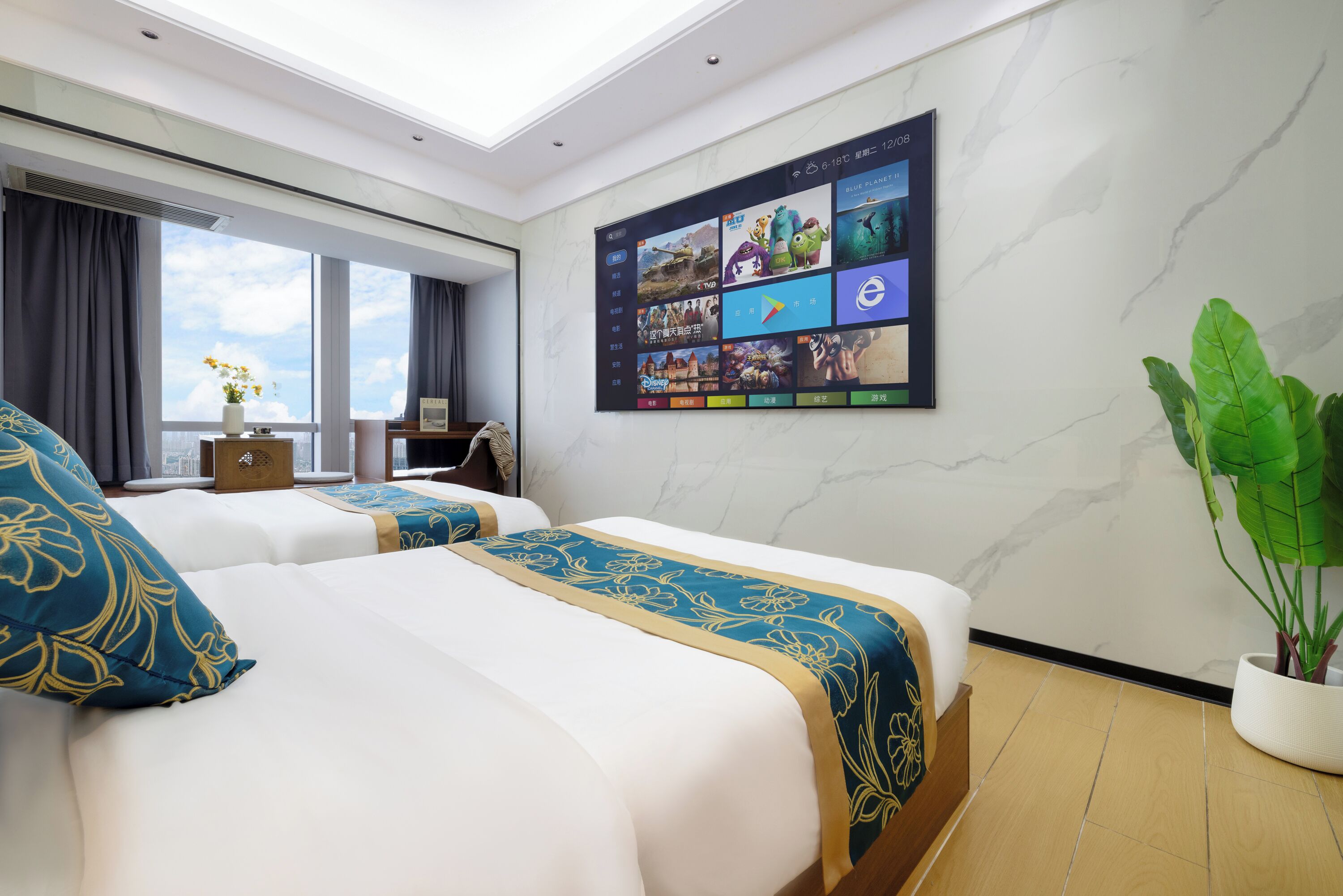 A hotel room with two beds, a large window, a wall-mounted digital screen, and a potted plant.