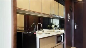 Una cocina compacta con un refrigerador negro, dos fregaderos y armarios de madera.