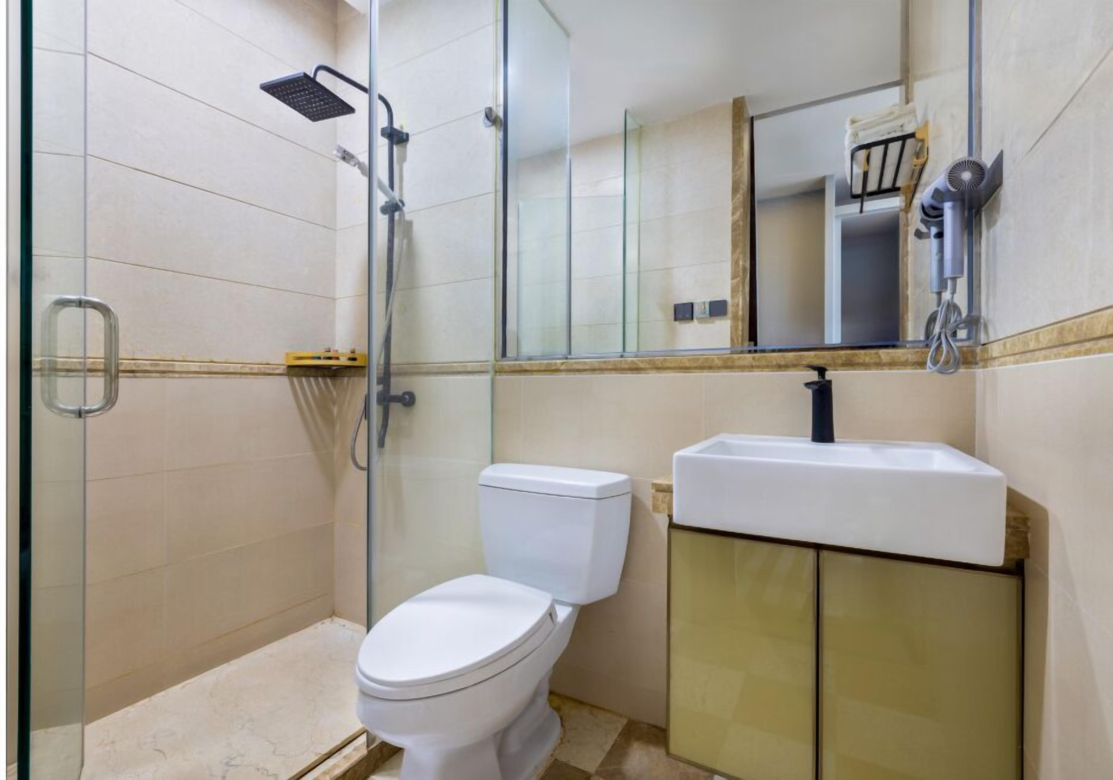 A modern bathroom with a glass shower enclosure, a white toilet, and a sink with a mirror above it.