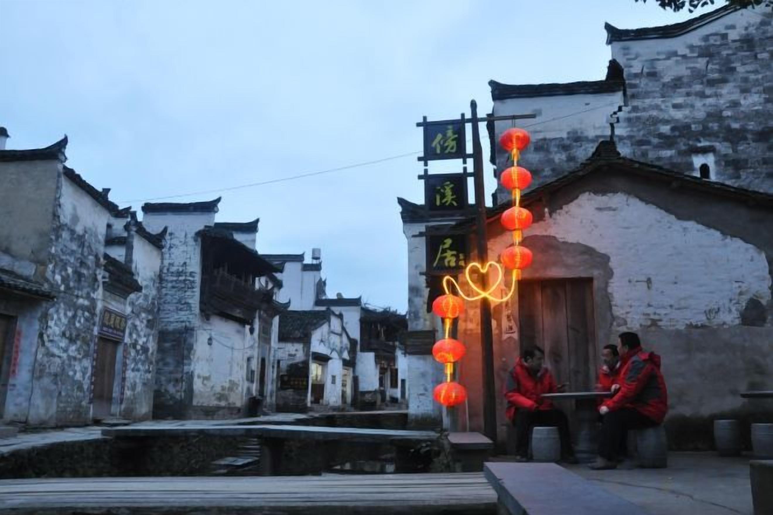 Um edifício tradicional com porta de madeira e fileira de lanternas vermelhas.