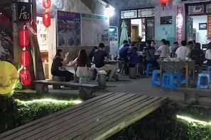 Un espace extérieur aménagé avec des tables et des tabourets, un banc en bois et un chemin.