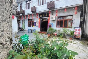 A traditional building with a signboard, outdoor seating, and potted plants. - Brook Hotel (Wuyuan)