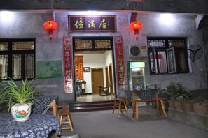 A traditional Chinese restaurant with a signboard, wooden furniture, and potted plants. - Brook Hotel (Wuyuan)