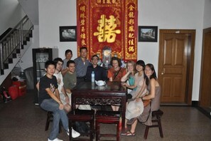 A group of people seated around a table in a room with a staircase and a door in the background. - Brook Hotel (Wuyuan)
