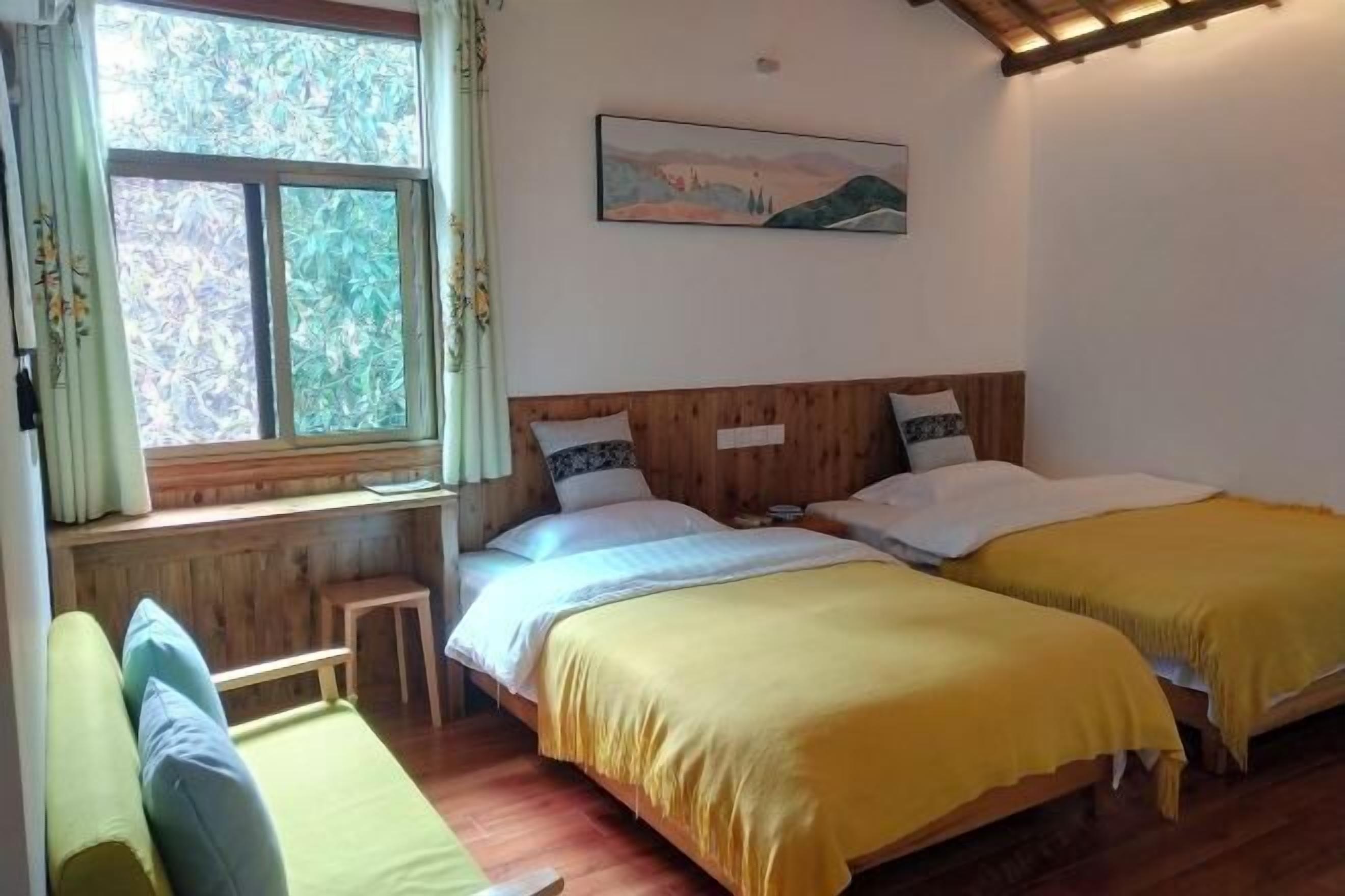Ein Zimmer mit zwei Holzbett, einer Bank, einem Fenster mit Vorhängen und einem Bild an der Wand.
