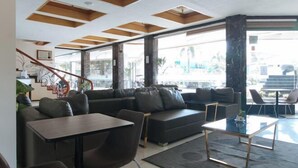 A modern living room with a sectional sofa, a coffee table, and a staircase leading to an upper floor. - RedDoorz Premium @ Nick Hotel Gerona Tarlac (Gerona)