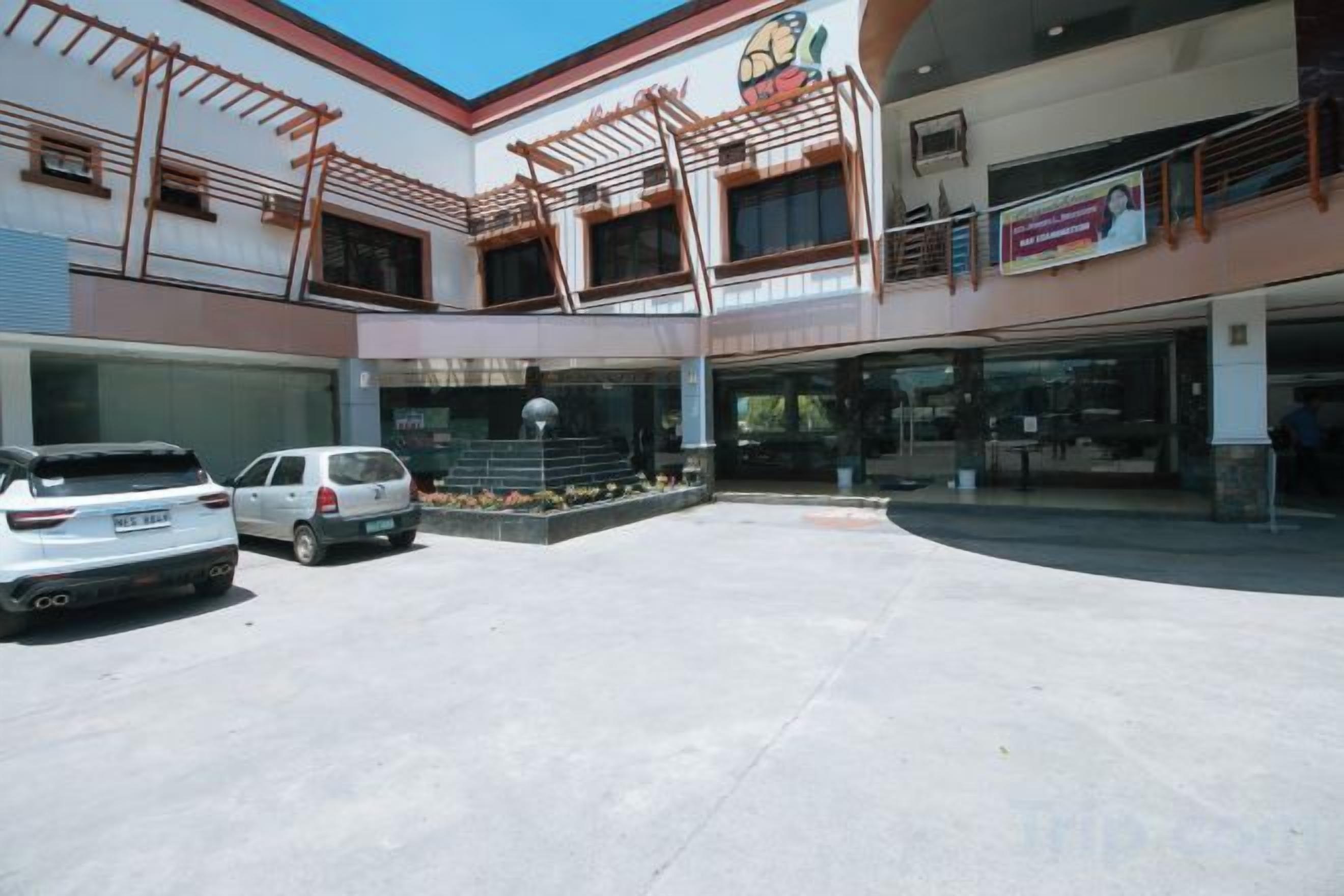 A multi-level building with a covered outdoor area, a car parking lot, and a storefront.
