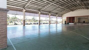 A large indoor space with a high ceiling and a concrete floor, featuring a central open area with a view of the outside.