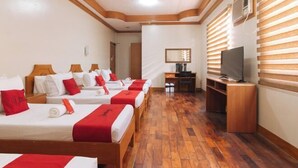 A hotel room with four single beds, wooden flooring, a desk with a chair, a television, and a mirror on the wall. - RedDoorz Premium @ Nick Hotel Gerona Tarlac (Gerona)
