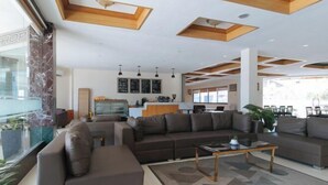 A modern living room with a sectional sofa, a coffee table, and a kitchen area in the background. - RedDoorz Premium @ Nick Hotel Gerona Tarlac (Gerona)