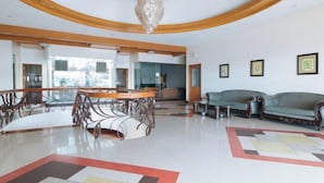 A spacious living area with a large wooden table, a sofa, and a chandelier. - RedDoorz Premium @ Nick Hotel Gerona Tarlac (Gerona)