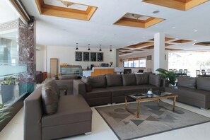 A modern living room with a sectional sofa, a coffee table, and a large window. - RedDoorz Premium @ Nick Hotel Gerona Tarlac (Gerona)