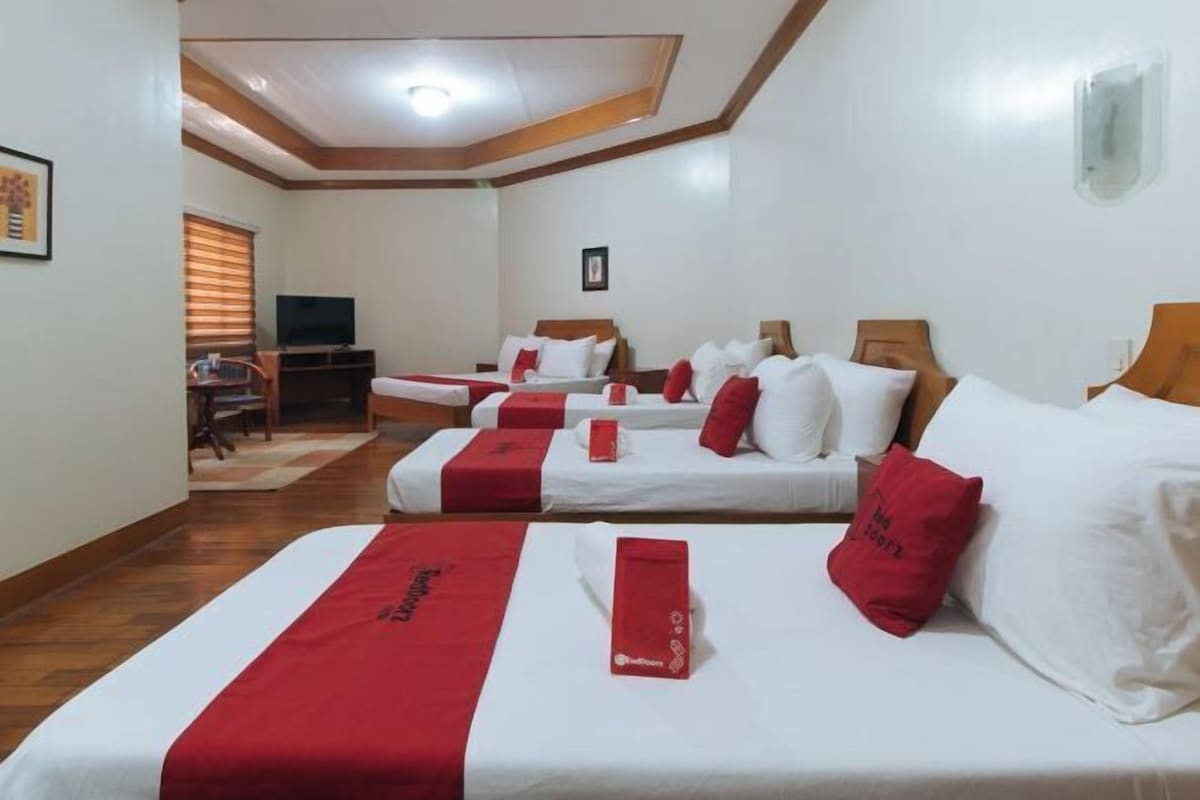 A hotel room with two beds, a TV, and a desk.