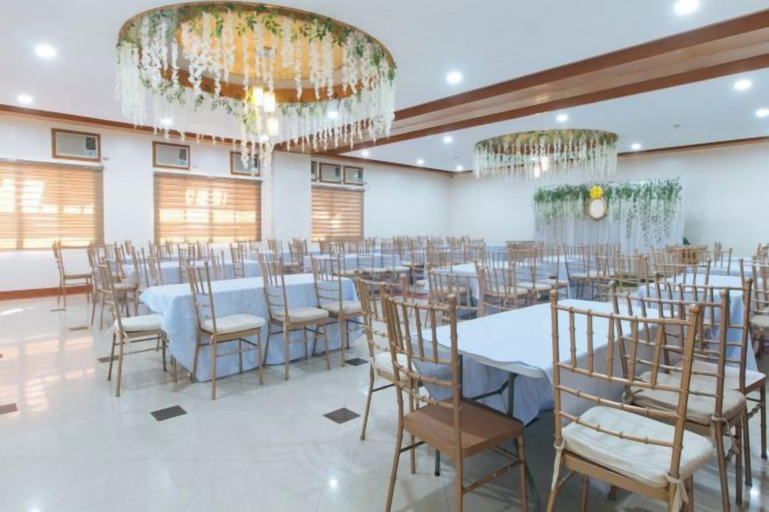 A banquet hall with round tables, chairs, and a chandelier.