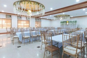 Un salón de banquetes con mesas redondas, sillas y una araña.