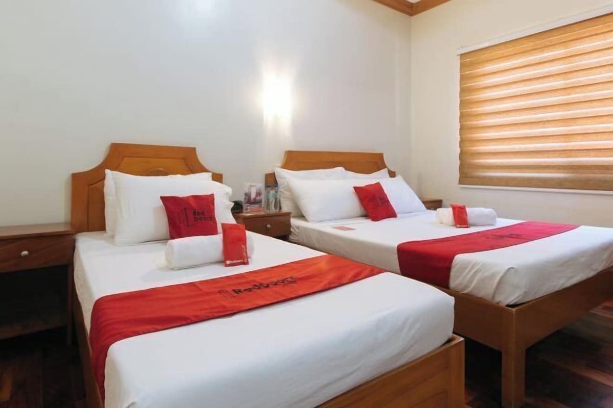 Two single beds with wooden headboards, white bedding, and red accents.