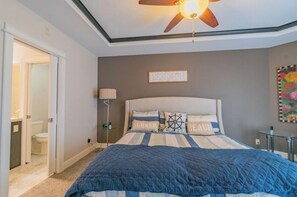 Quarto com cama, ventoinha no teto, mesa de cabeceira e apoio para objetos.
