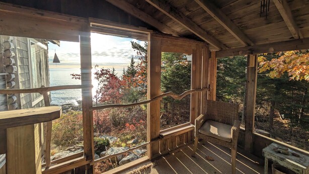 A wooden cabin with large windows overlooking a lake and autumn foliage. - Oceanfront Cabin-Castle in Maine Woods (Georgetown)