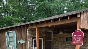 Un edificio rústico de madera con fachada de piedra, una mesa de picnic y asientos al aire libre.