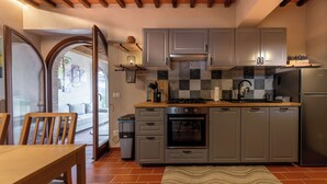 A compact kitchen with grey cabinets, a built-in oven, and a stainless steel refrigerator. - Refined Home W/ Pool, Stunning View, and Relaxing (Volterra)