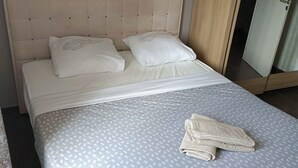 Un lit bien fait, avec une couvre-lit à motifs, deux oreillers et une serviette pliée posée sur le lit.