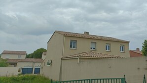 Un bâtiment à deux étages, doté d’un toit recouvert de tuiles et d’une façade beige.