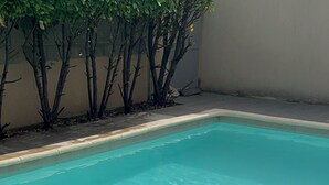 Une piscine d’un bleu éclatant, avec un bord carrelé et une bordure en béton.