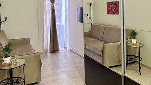 A modern living room with two sofas, a glass coffee table, a small side table, and a large mirror. - Centro Storico Napoli • 2 Camere • Balcone • Famiglie e Gruppi (Napoli)