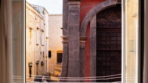A balcony with two chairs, a wrought iron railing, and a view of a narrow street with buildings and an archway. - Centro Storico Napoli • 2 Camere • Balcone • Famiglie e Gruppi (Napoli)