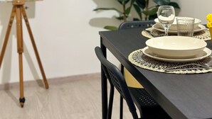 A dining area with a table set for two, a painting on the wall, and a potted plant. - Centro Storico Napoli • 2 Camere • Balcone • Famiglie e Gruppi (Napoli)