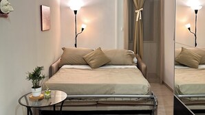 A modern bedroom with a bed, bedside lamps, a small table with a plant, and a mirror. - Centro Storico Napoli • 2 Camere • Balcone • Famiglie e Gruppi (Napoli)