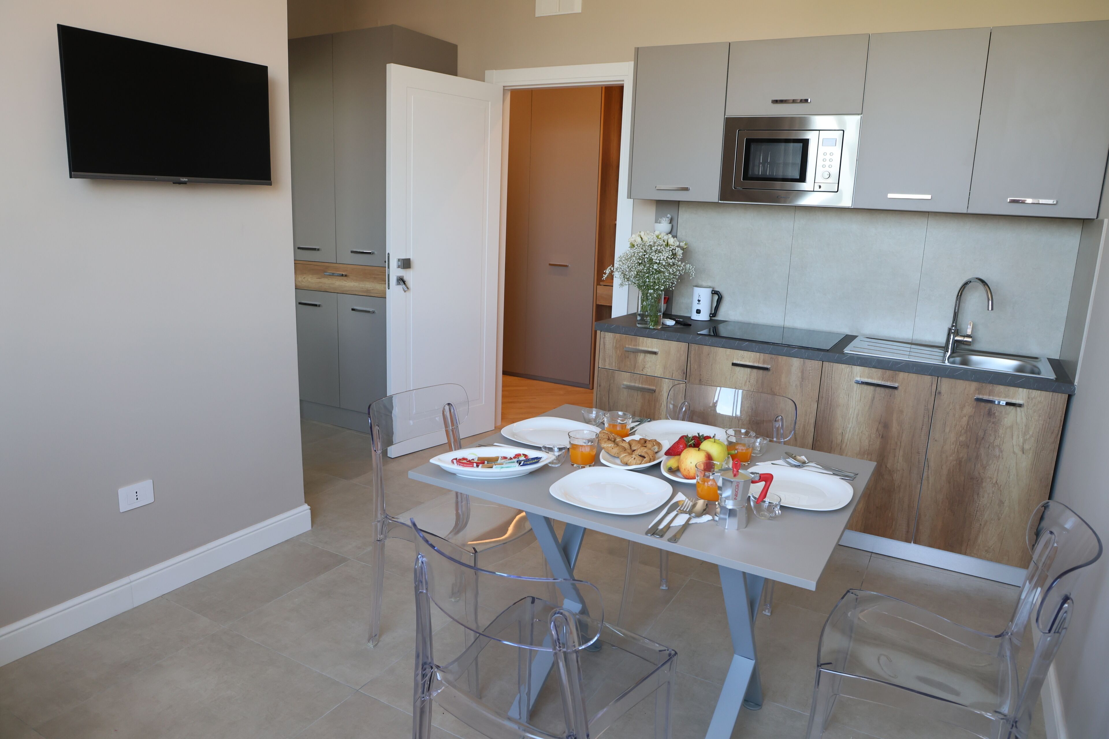Una cocina moderna con gabinetes grises, microondas integrado y un comedor con mesa lista para el desayuno.