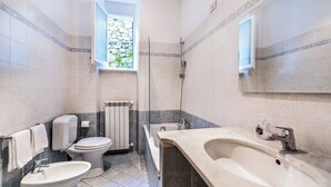 Een badkamer met toilet, bidet, wastafel en douche.