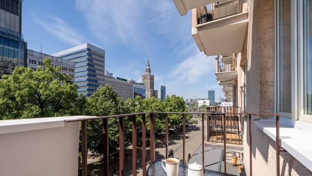 A balcony with a table, a cup, and a pot.