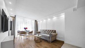 A modern living room with a sofa, two chairs, a coffee table, and a TV mounted on the wall.