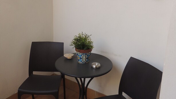A small patio area with two black chairs, a round table, and a potted plant.