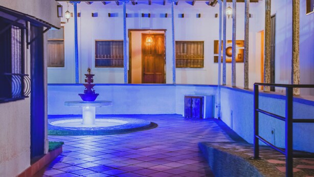A courtyard with a fountain, tiled floor, and a wooden door. - Raizes AXM (Circasia)