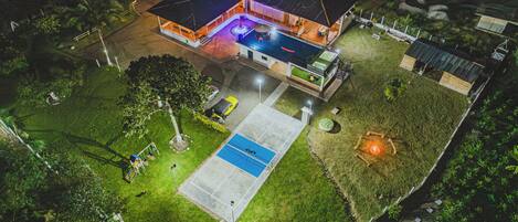 An aerial view of a house with a swimming pool, a covered patio, and a fenced yard.