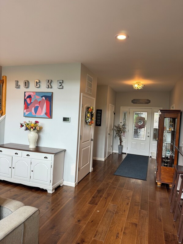 A hallway with a white cabinet, a vase with flowers, and a sign that reads "LOCKE".