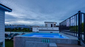 Une piscine sur le toit offrant une vue sur la ville, des chaises longues et un espace aménagé au bord de la piscine.