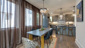 Une cuisine moderne dotée d’un îlot central, de tabourets de bar et d’un lustre.