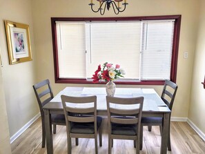 A dining room with a rectangular table, four chairs, a vase with flowers, and a chandelier. - Nice big house with parking, fenced yard (Buffalo)