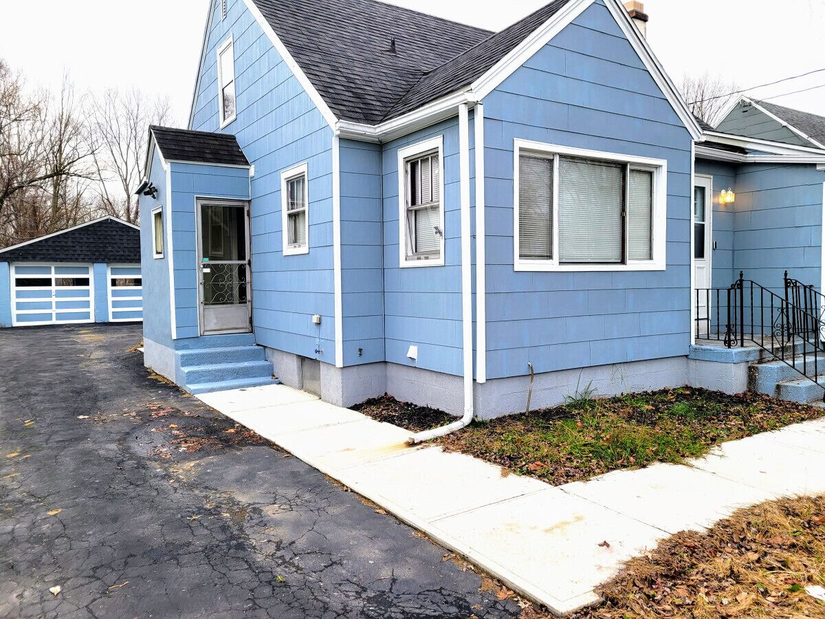 A residential house with a blue exterior, a front porch, and a driveway.