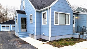 A residential house with a blue exterior, a front porch, and a driveway. - Nice big house with parking, fenced yard (Buffalo)