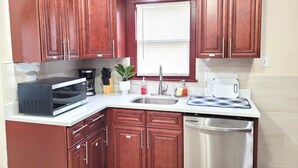 A kitchen with wooden cabinets, a microwave, a sink, and a dishwasher. - Nice big house with parking, fenced yard (Buffalo)