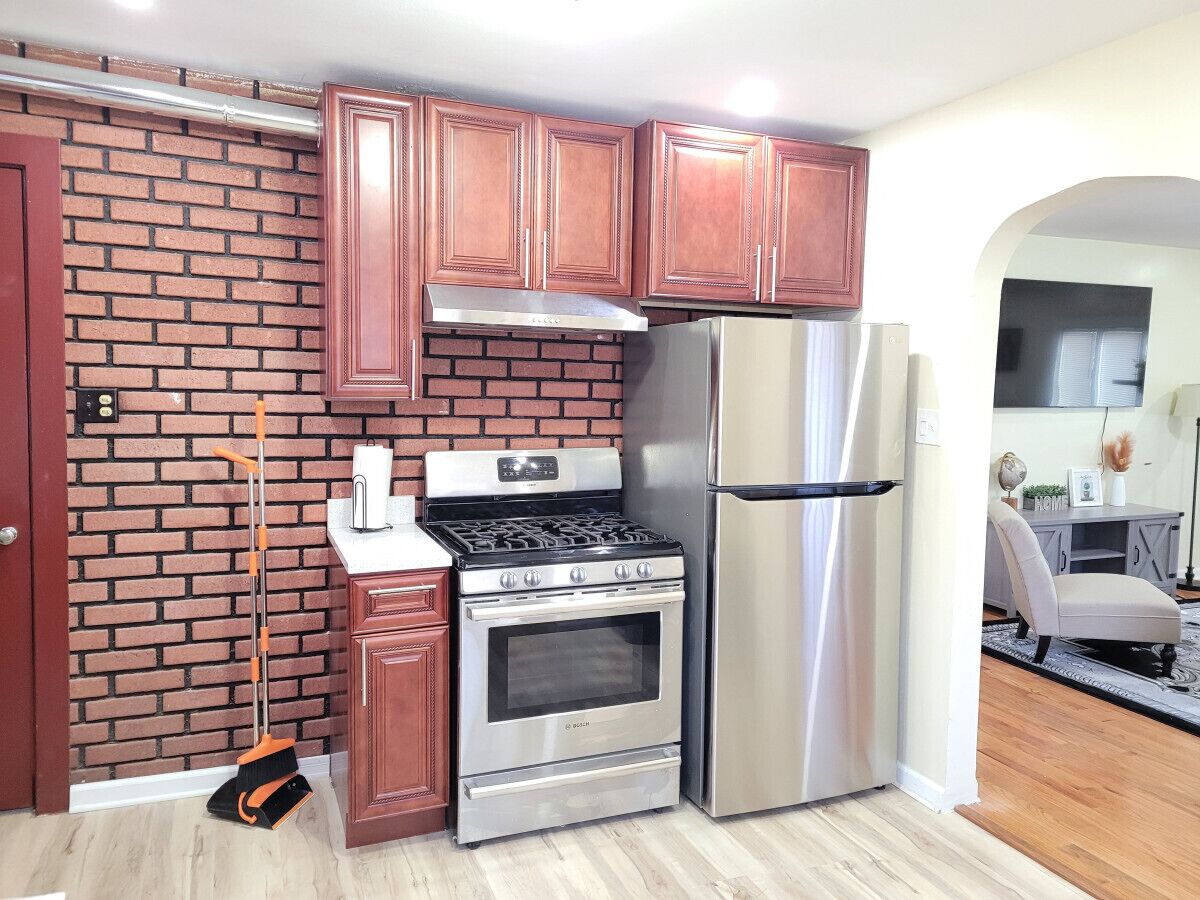 A kitchen with a brick wall, stainless steel appliances, and wooden cabinets.