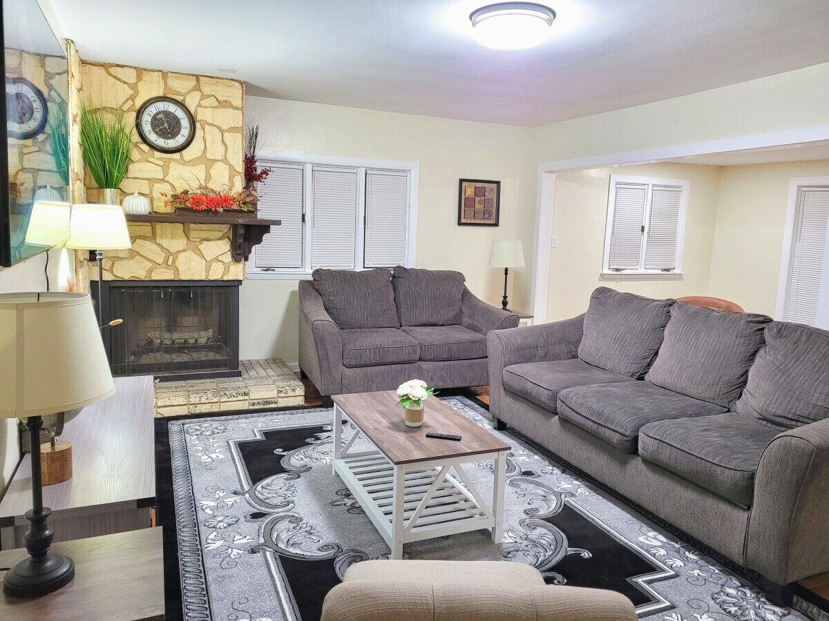 A living room with a fireplace, two sofas, a coffee table, and a patterned rug.