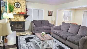 A living room with a fireplace, two sofas, a coffee table, and a patterned rug.