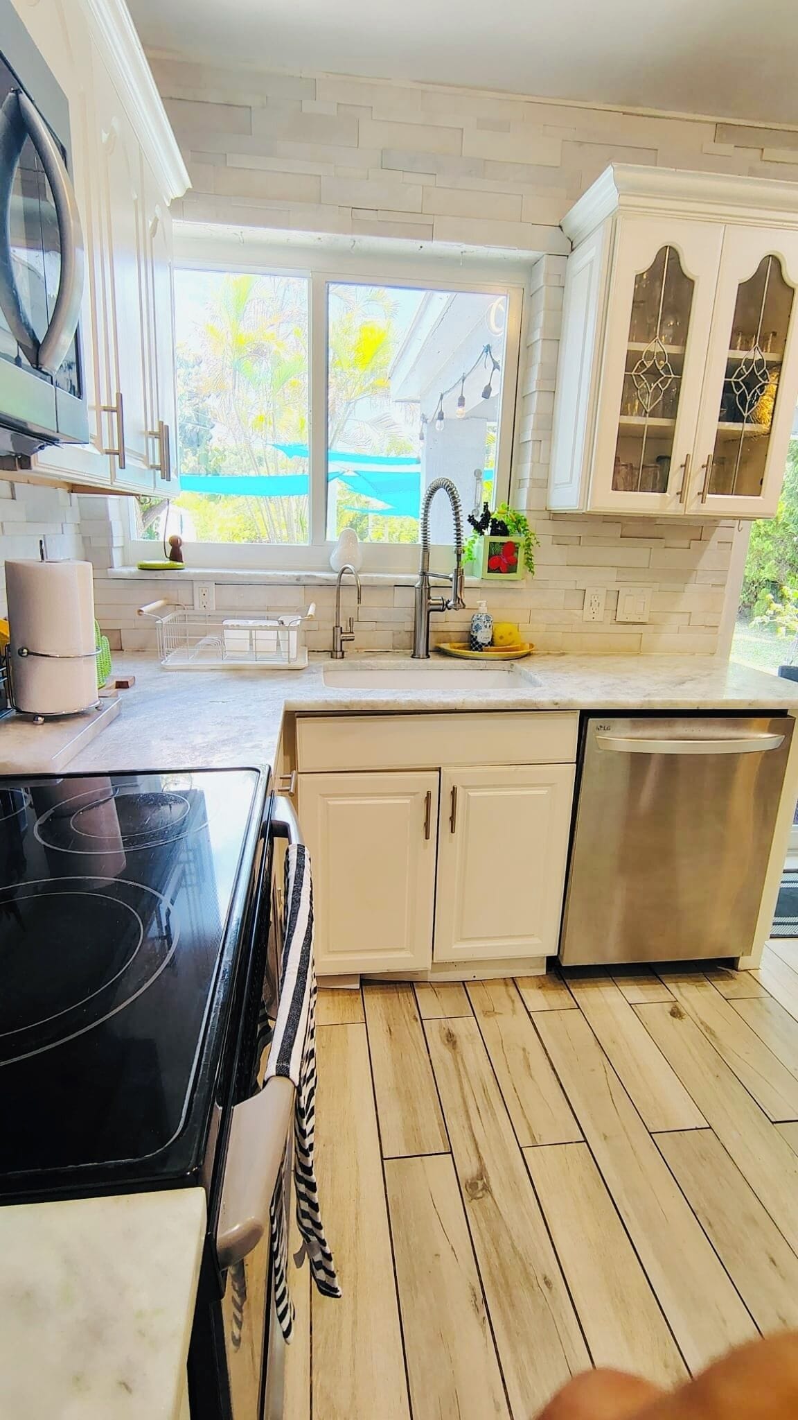 A kitchen with a stove, sink, cabinets, and a dishwasher.